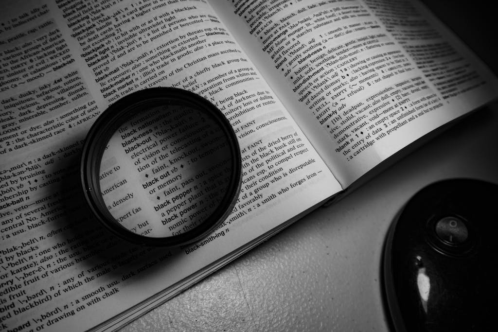 A monochrome image of a lens on an open dictionary page, highlighting words.