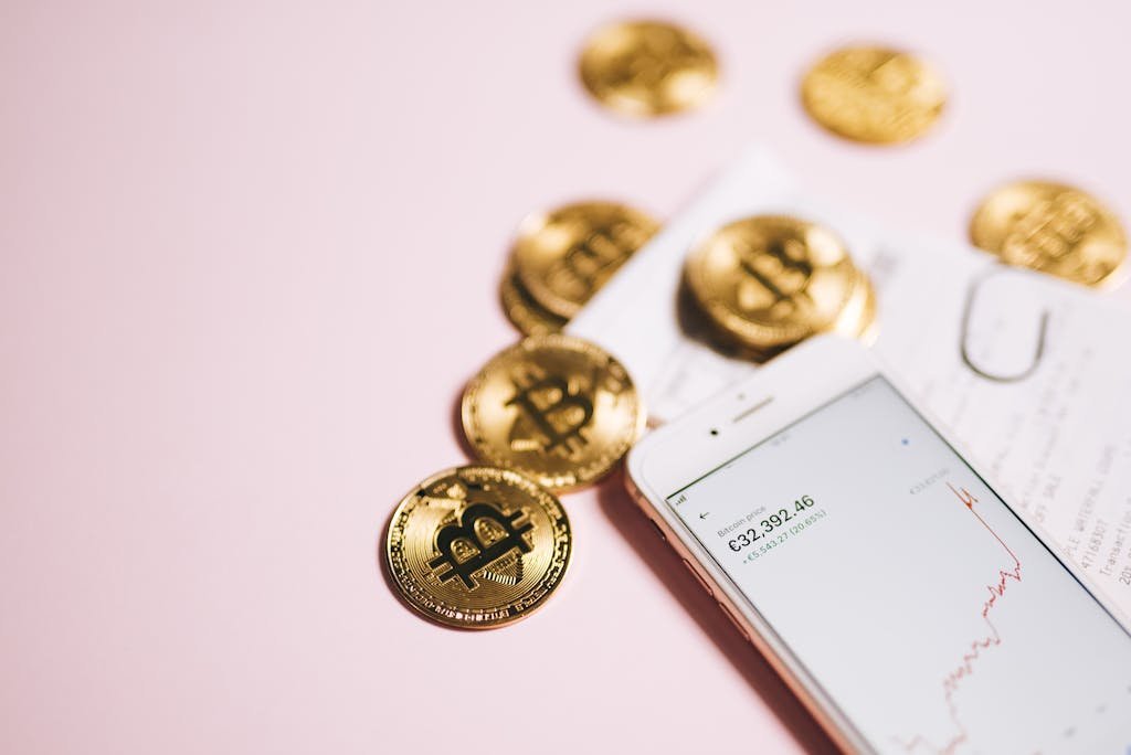 Bitcoin coins with a smartphone displaying financial data, symbolizing cryptocurrency and digital investments.