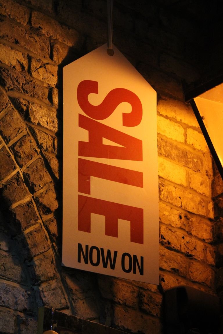 A bright sale sign hangs on a rustic brick wall, creating a warm shopping ambiance.