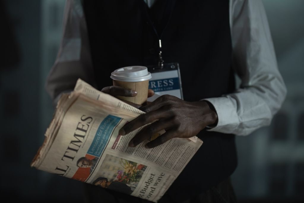 Close-up of a journalist holding a newspaper and coffee cup, conveying press and media concept.