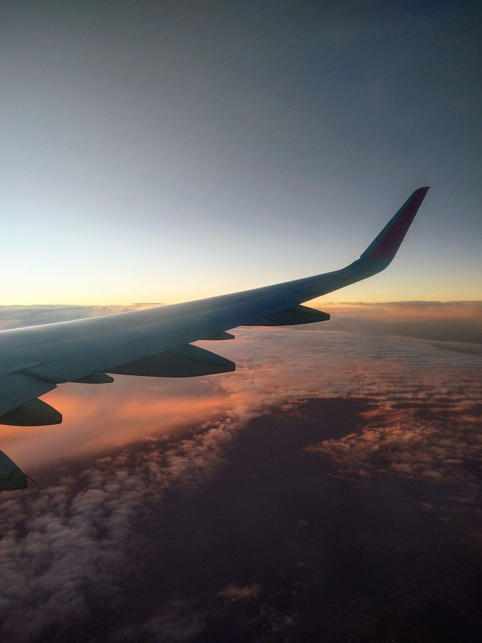 Stunning view of airplane wing above colorful clouds during sunset flight.