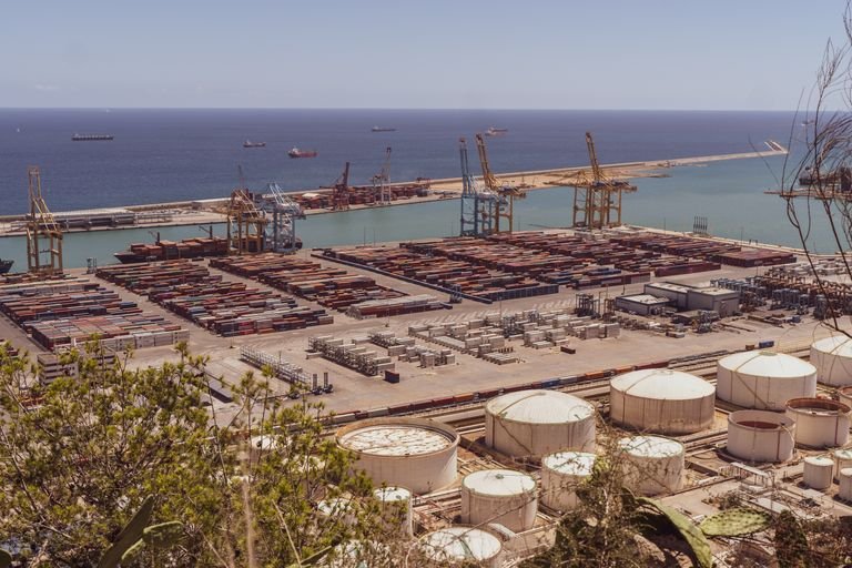 A busy industrial port with cranes and cargo containers alongside the sea.
